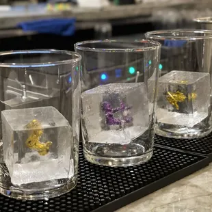 three glasses with ice cubes on a bar