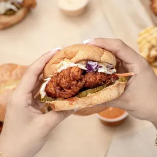 a person holding a chicken sandwich