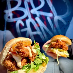 a hand holding a sandwich with chicken and lettuce
