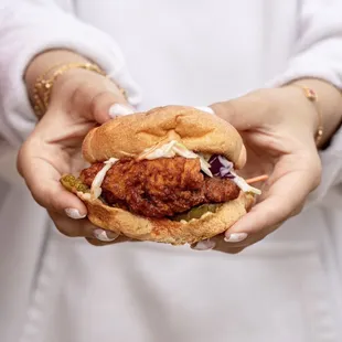 a woman holding a chicken sandwich