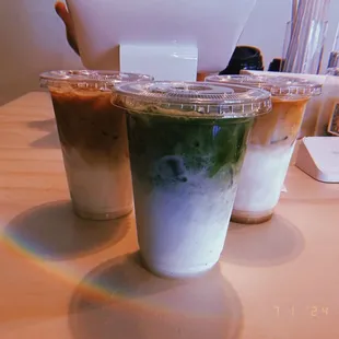One regular latte, a matcha latte, and a honey latte all iced.