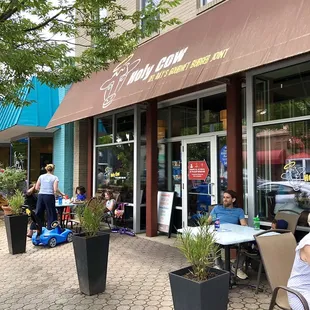 people sitting at tables outside a restaurant