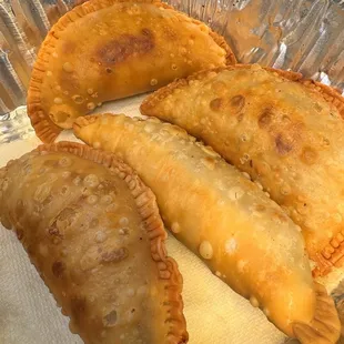three empanadas on a foil pan