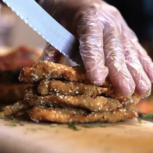 a chef&apos;s hands slicing up a sandwich