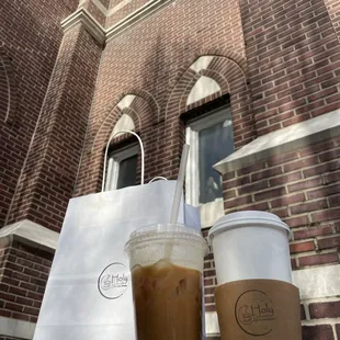 two cups of coffee and a paper bag
