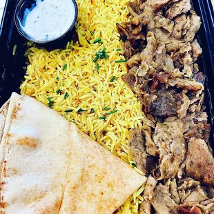 a tray of food including rice, meat, and a pita