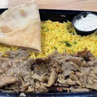 a plate of food with rice, meat and pita