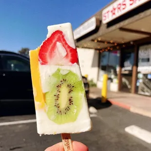 a hand holding a piece of fruit on a stick