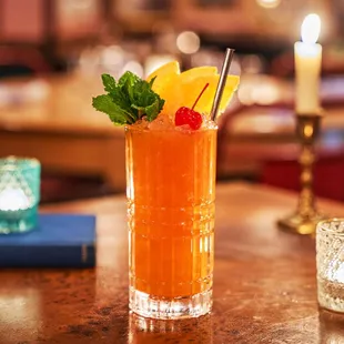 a tall glass of orange juice on a table