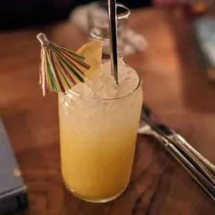 a glass of orange juice with an umbrella
