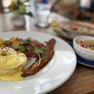Chef&apos;s Special (Classic Eggs Benedict, Bacon, Roasted Potatoes, Portuguese Sausage) with a side of yogurt with granola and fresh berries