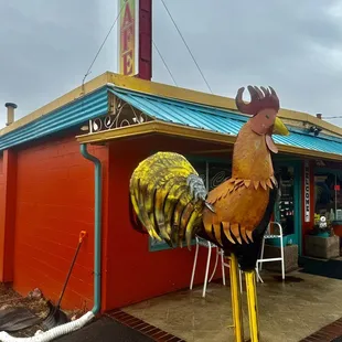 a rooster statue in front of a restaurant