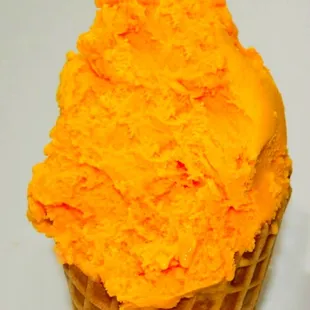 a waffle cone filled with orange colored ice cream