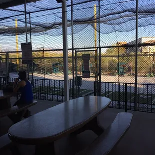a man sitting at a table in a batting cage