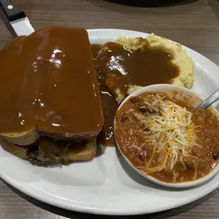 Hot beef sandwich with a side of chili.