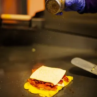a sandwich being sprinkled with salt