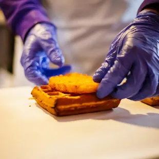 a person in purple gloves making a sandwich
