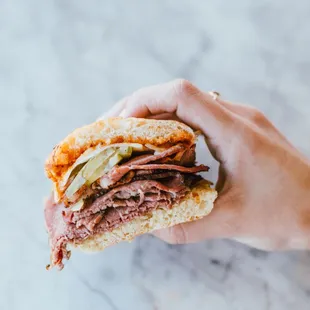 Our Smoked Pastrami sandwich made with melty cheese, caramelized onions, smoked aioli &amp; dill pickle