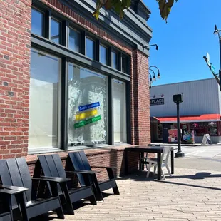 a row of black plastic chairs in front of a brick building