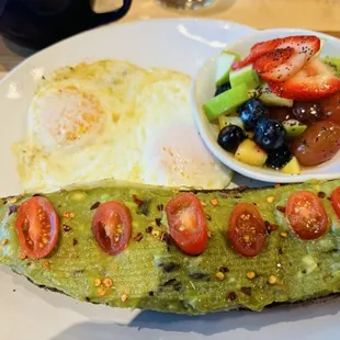 Avocado toast with fried eggs and fresh fruit