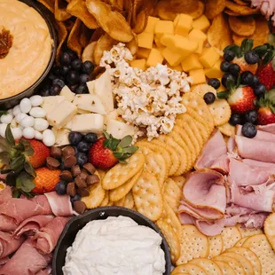 a platter of cheese, meat, crackers, and fruit