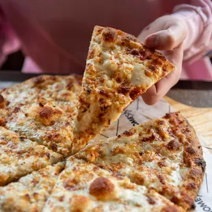 a person taking a slice of pizza