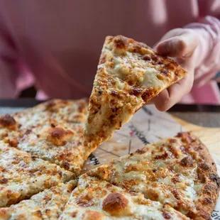 a person taking a slice of pizza