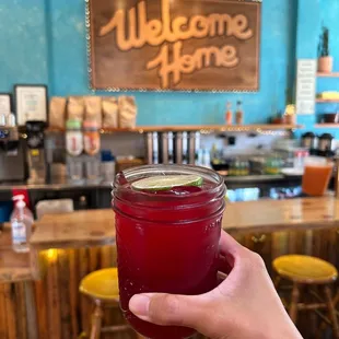a hand holding a jar of red liquid