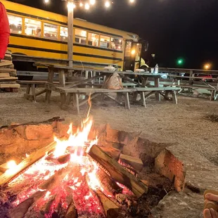a campfire with a school bus in the background