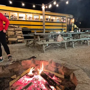 a woman standing in front of a campfire