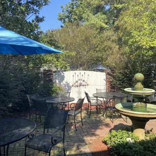 a patio with tables and chairs and a fountain