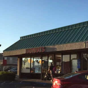 a red car parked in front of a donut shop