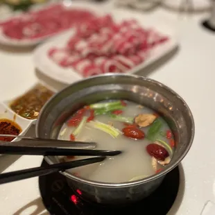 a hot pot of soup with chopsticks