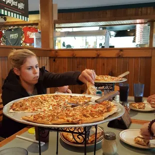 Thin crust pizza in front, and my sister inlaw in front of a thick crust pepperoni pizza.