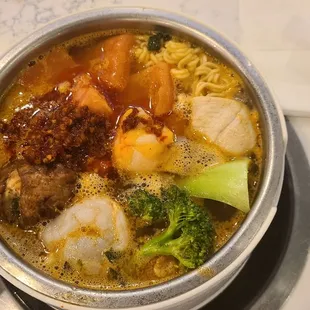 Assortment of veggies and meats cooking in broth at your table