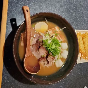 a bowl of ramen with a wooden spoon
