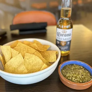 a bowl of tortilla chips and a bottle of corona beer
