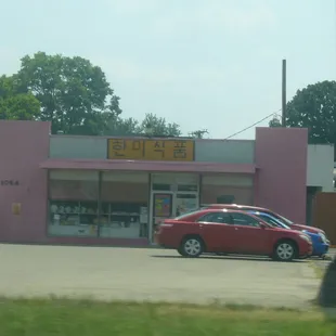 a red car parked in front of a pink building