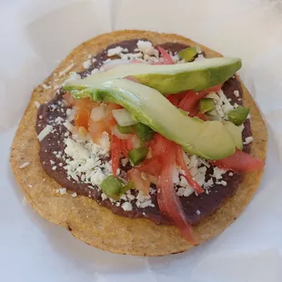 a tortilla topped with avocado and tomatoes