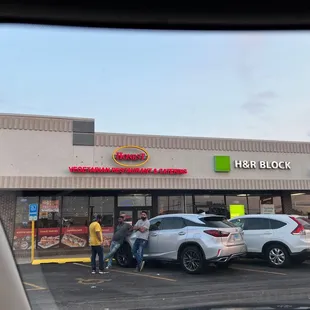 two people standing outside of a fast food restaurant