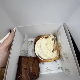 a hand holding a piece of cake and a piece of brownie