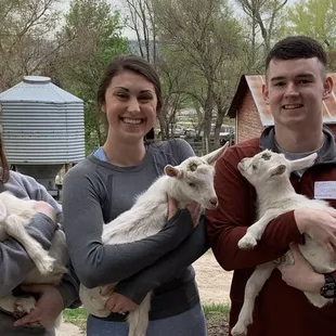 three people holding baby goats