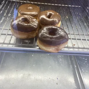 three chocolate frosted donuts on a cooling rack