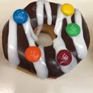 a chocolate donut with white icing and colorful candies