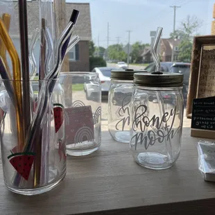 a glass jar with a straw, a glass jar with a straw, and a glass jar with