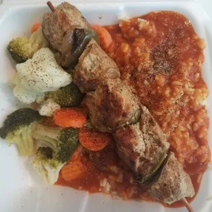 a plate of meat skewers and vegetables