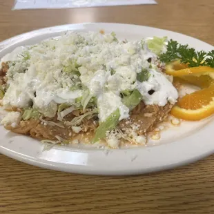 Chilaquiles Rojo. House made red sauce, fresh tortilla chips, juicy shredded chicken, lettuce, sour cream, and queso fresco.