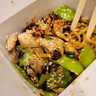 chopsticks and noodles in a takeout box