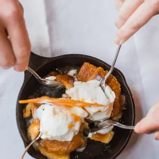 a person holding a spoon and scooping some ice cream into a skillet