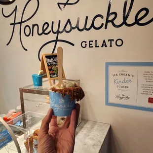 a hand holding a cup of gelato